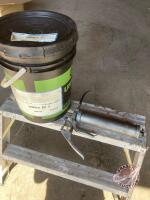 grease gun and near full pail of grease<br/>